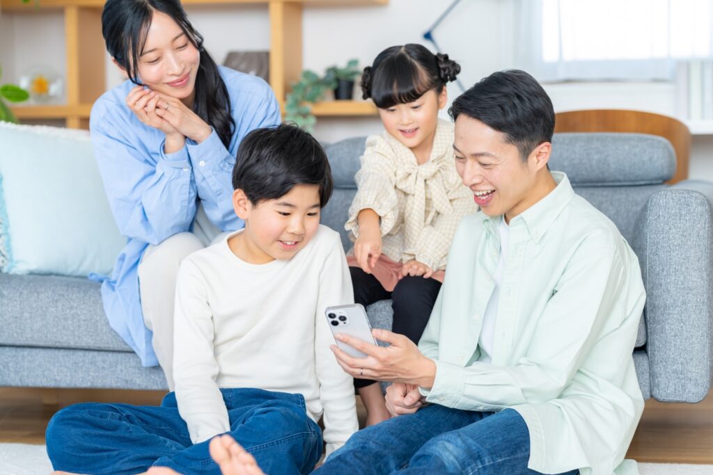 リビングで習い事のホームページをスマートフォンで閲覧している浦安・新浦安に住む4人家族
