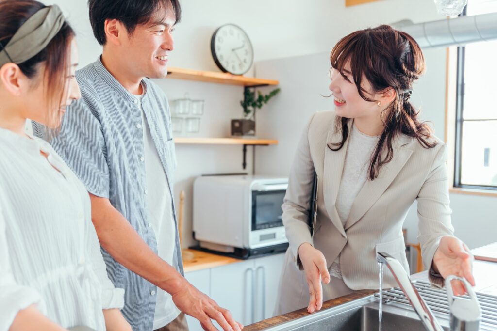 内見している夫婦とキッチンの説明をしている女性